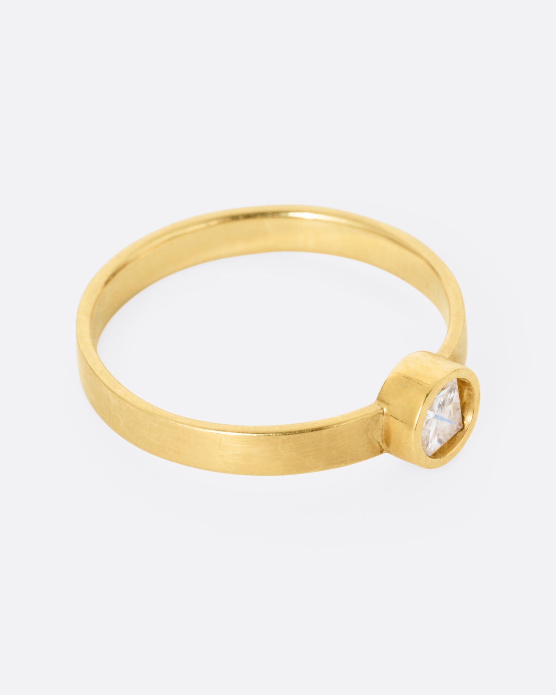 side view of a round yellow gold hole has a diamond set floating into the middle of it. there is a medium wide band that the setting is attached to and the gold is matte.