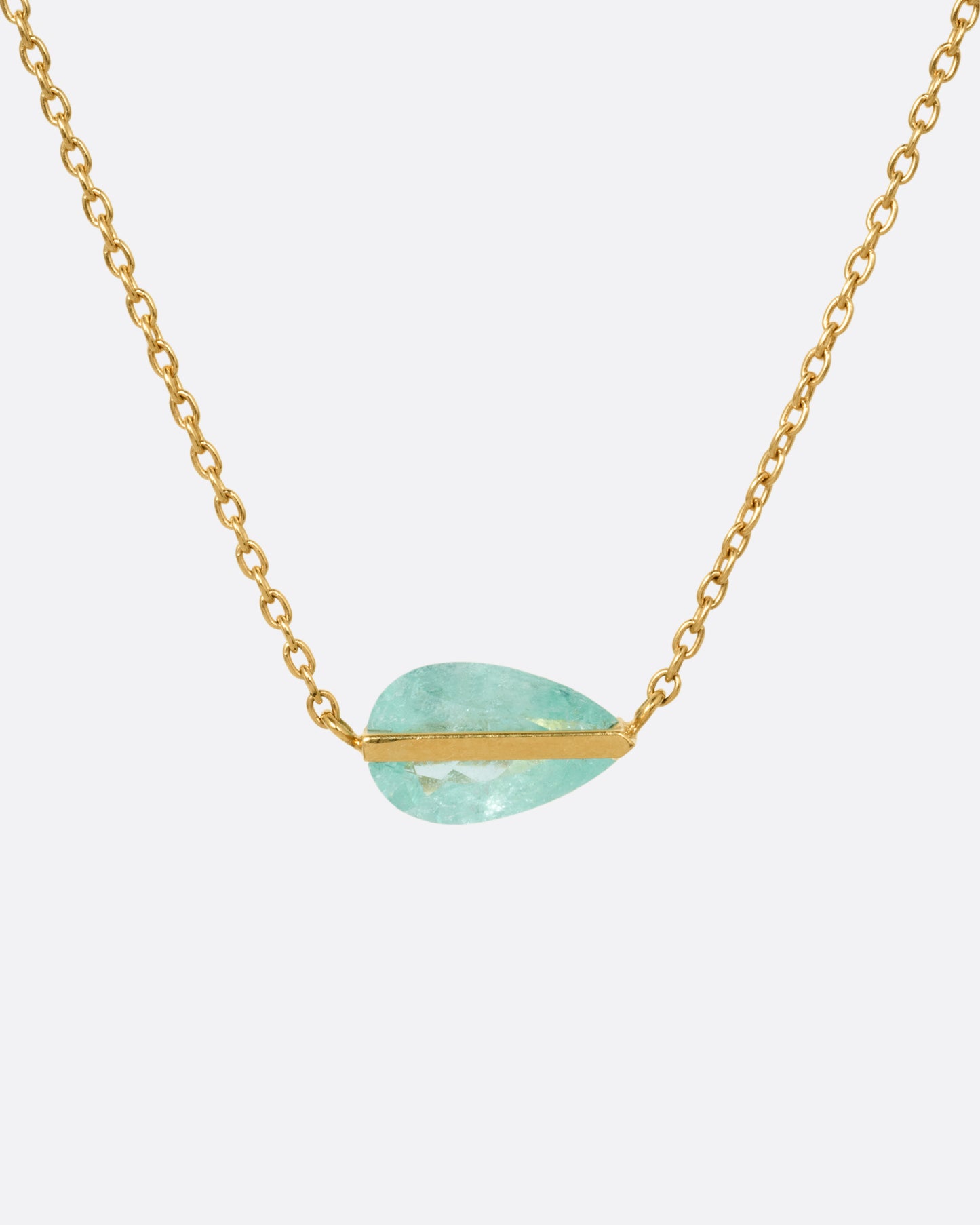 A yellow gold cable chain necklace with a blue-green Paraiba tourmaline pendant, shown from the front.