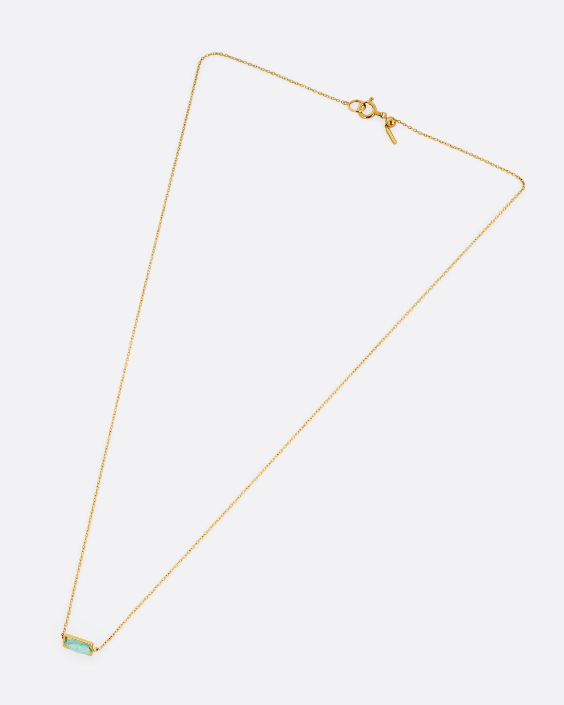 A yellow gold cable chain necklace with a blue-green Paraiba tourmaline pendant, shown from the front.