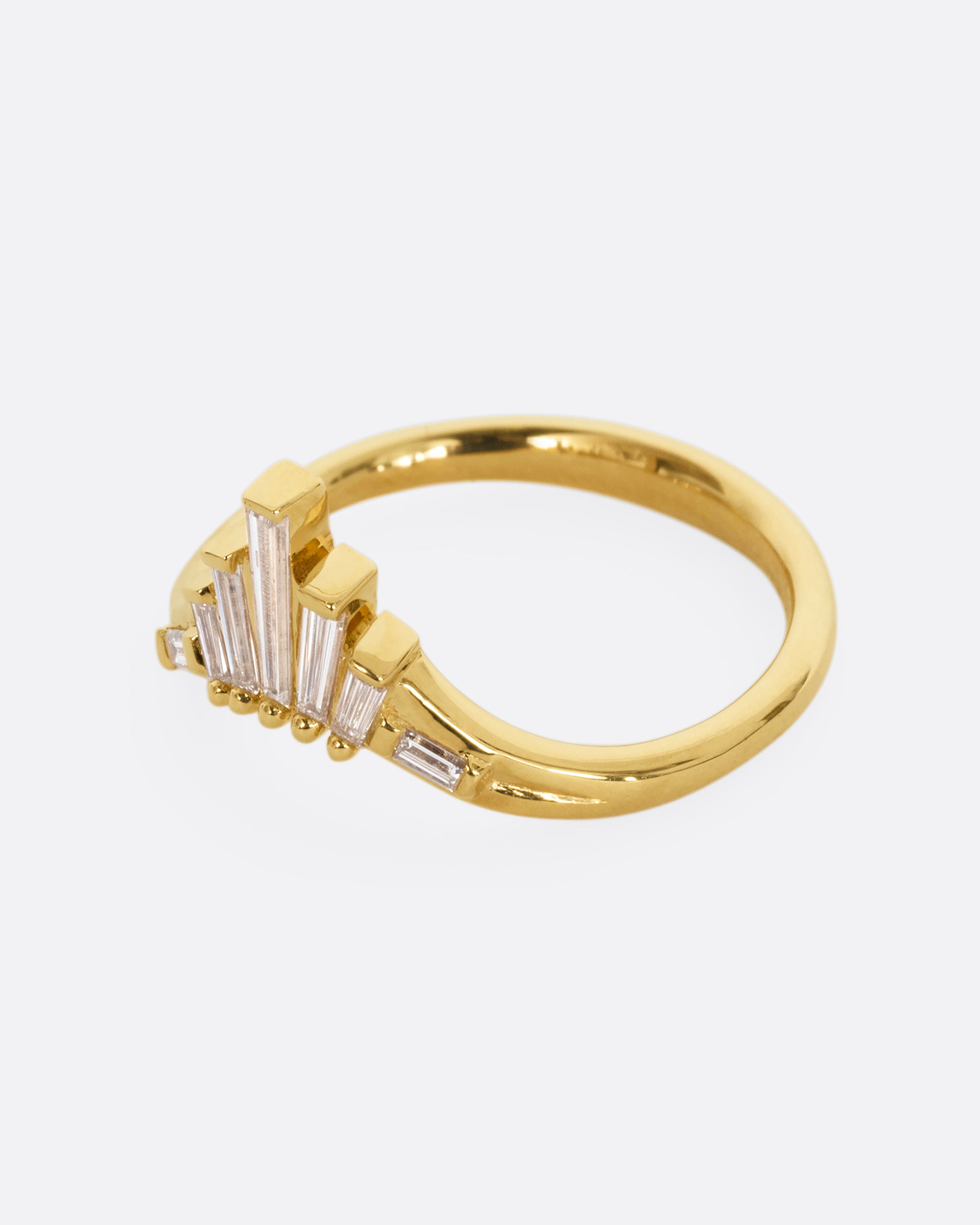 A yellow gold ring with graduated baguette diamonds. Shown from the side.