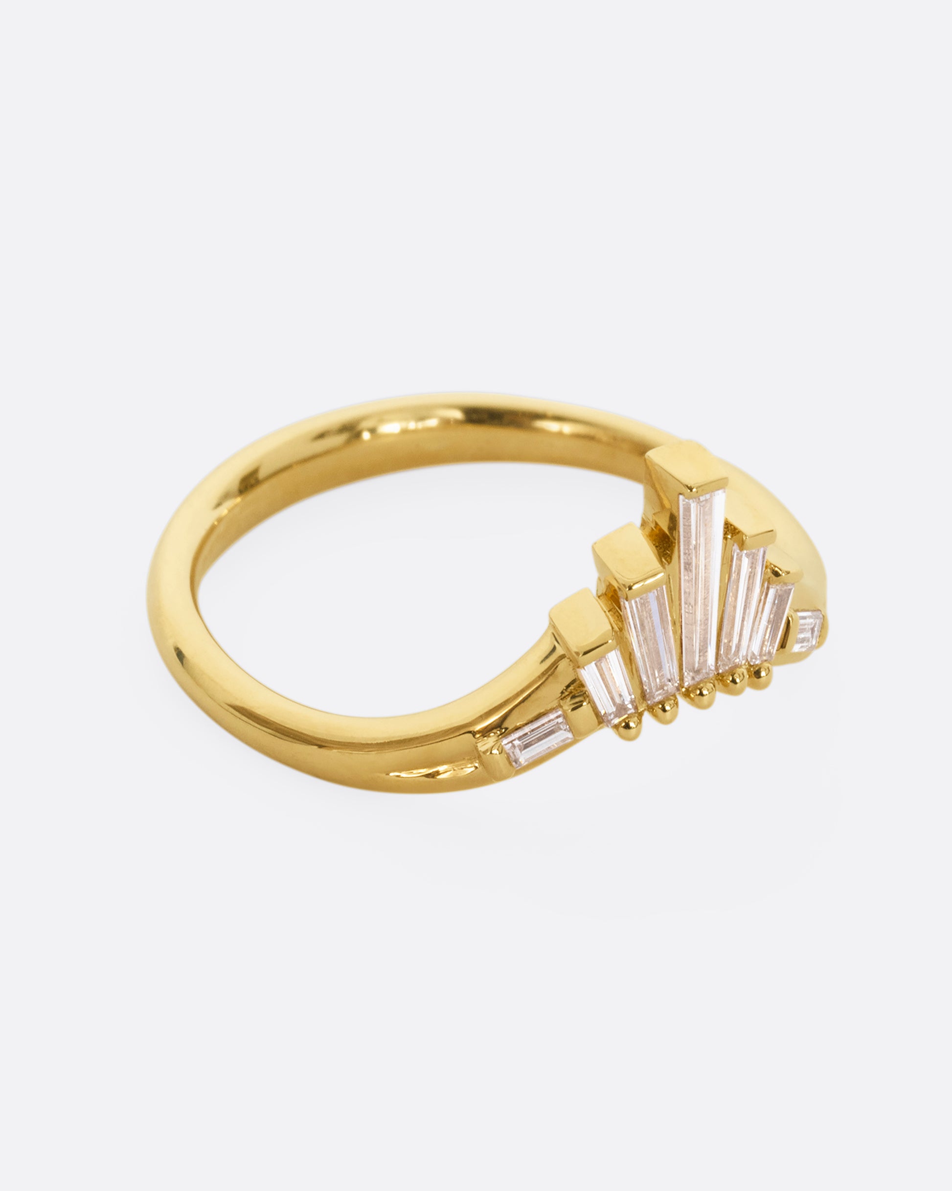 A yellow gold ring with graduated baguette diamonds. Shown from the side.