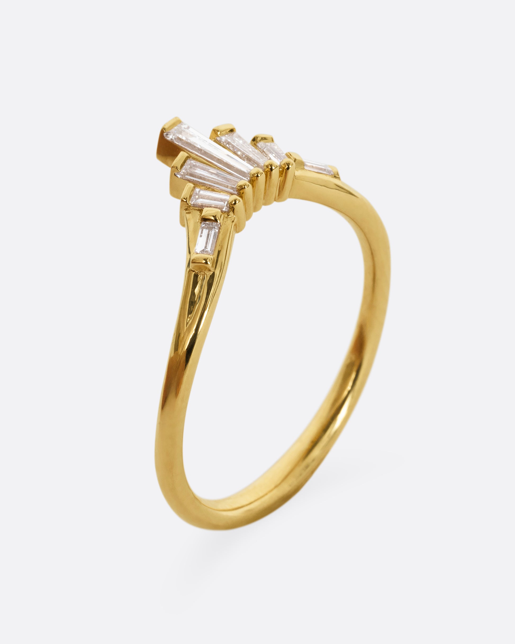 A yellow gold ring with graduated baguette diamonds. Shown from the side, standing up.