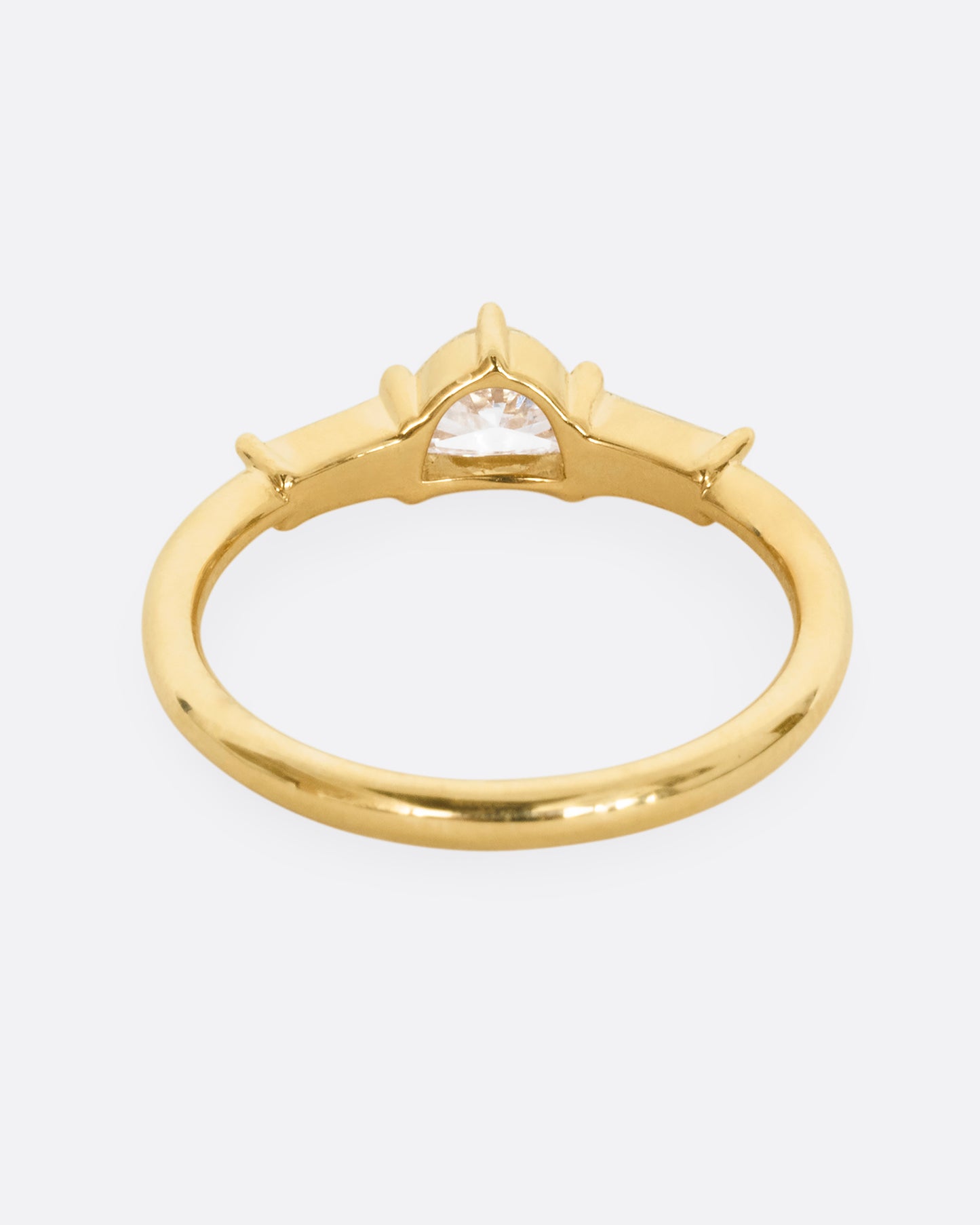 A yellow gold ring with a half moon shaped diamond and two baguette diamonds. Shown from the back.