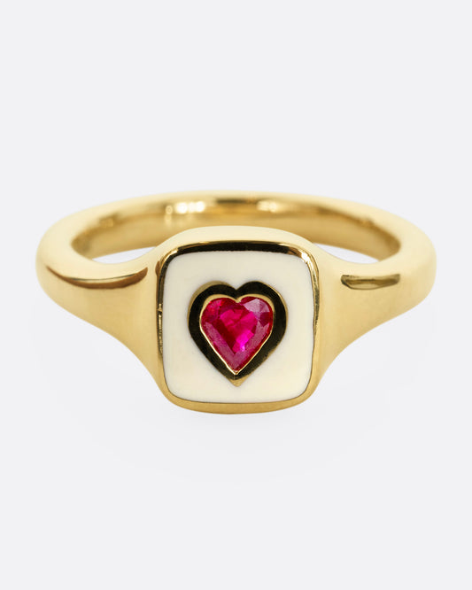 A yellow gold signet ring with cream enamel and a heart shaped ruby. Shown from the front.