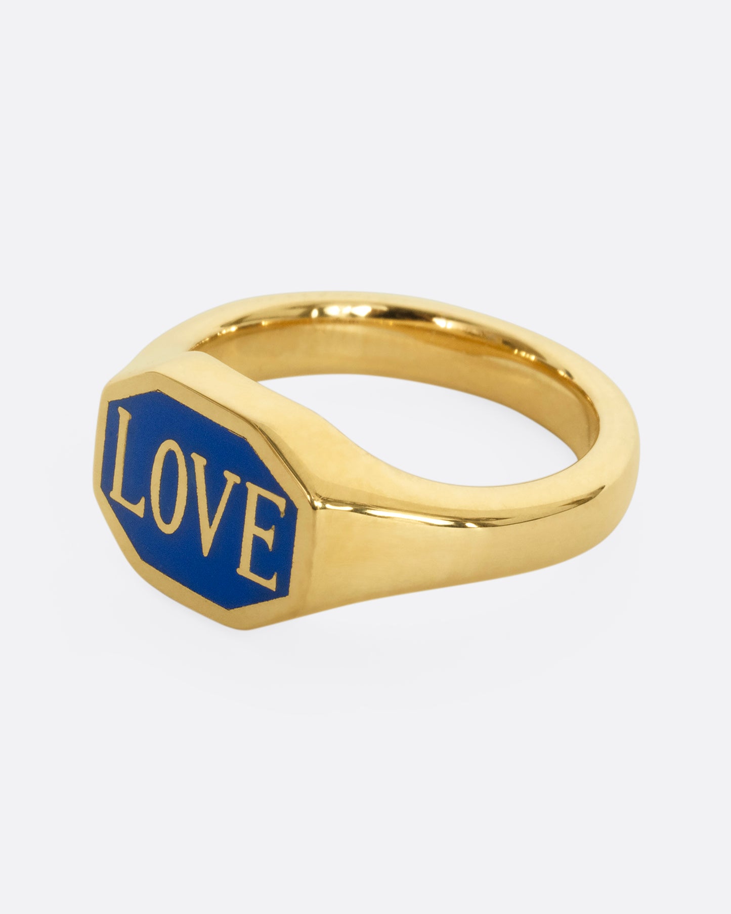 A yellow gold signet ring with blue enameled face with the word "Love". Shown from the side.