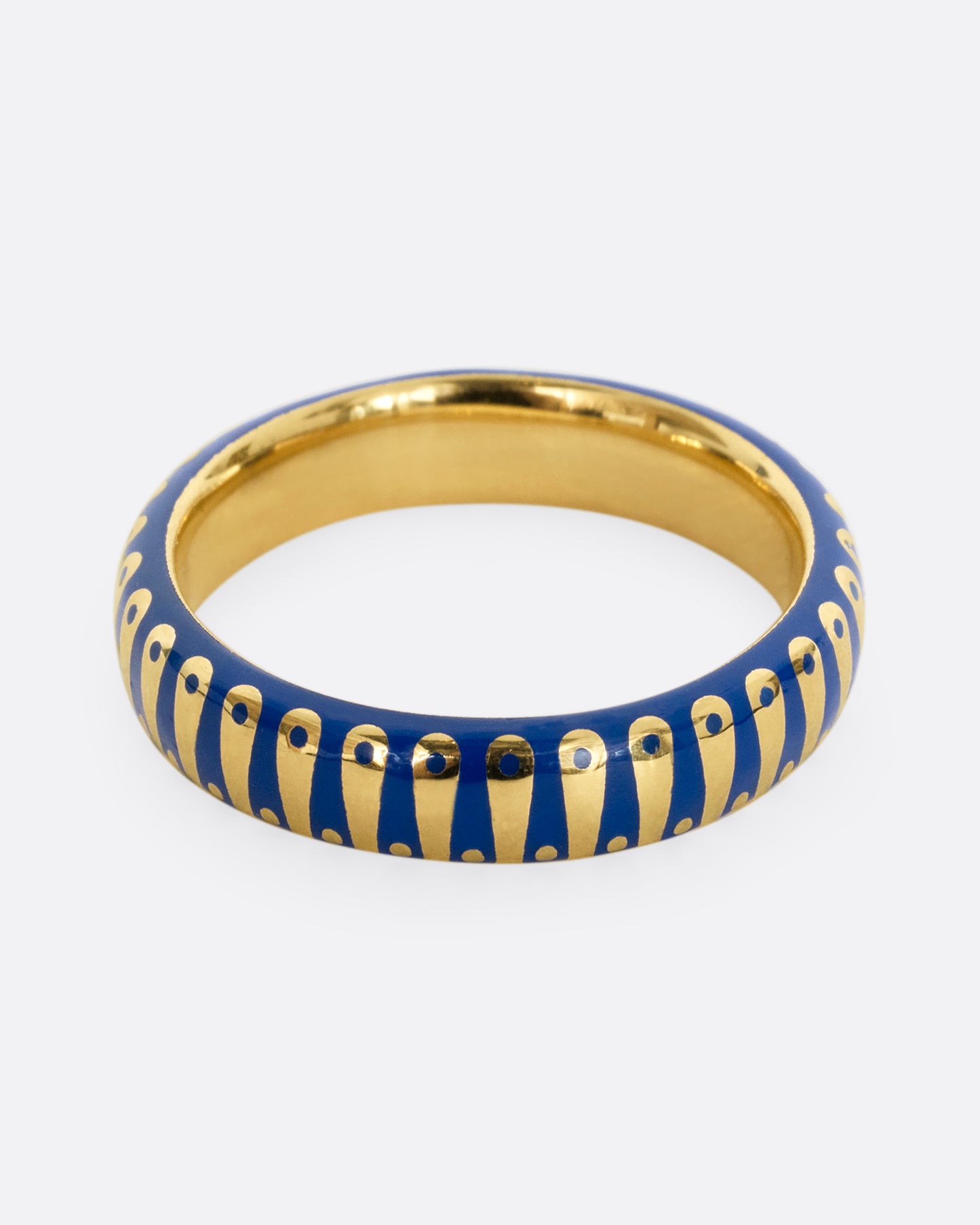 A yellow gold band ring with cobalt blue enamel stripes and dots. Shown from the front.