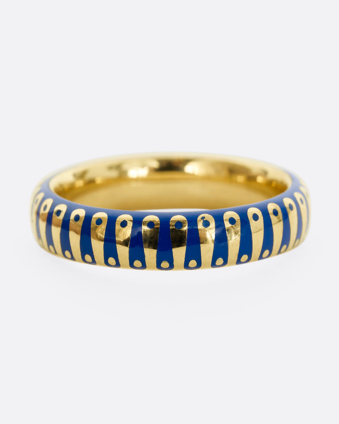 A yellow gold band ring with cobalt blue enamel stripes and dots. Shown from the front.