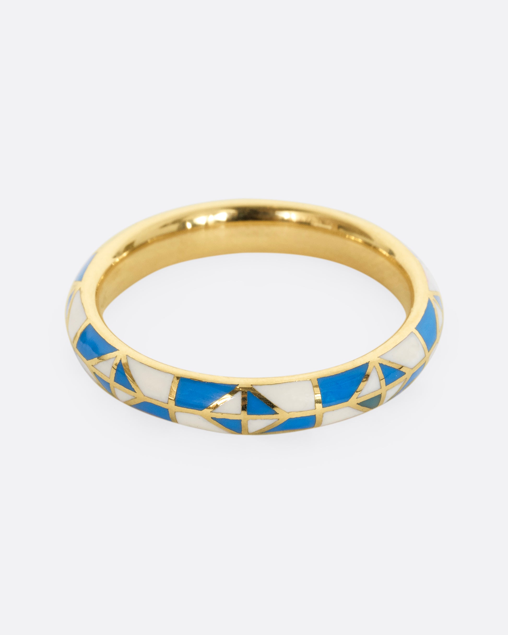 A yellow gold band ring with a turquoise and cream enamel patchwork pattern. Shown from the front.