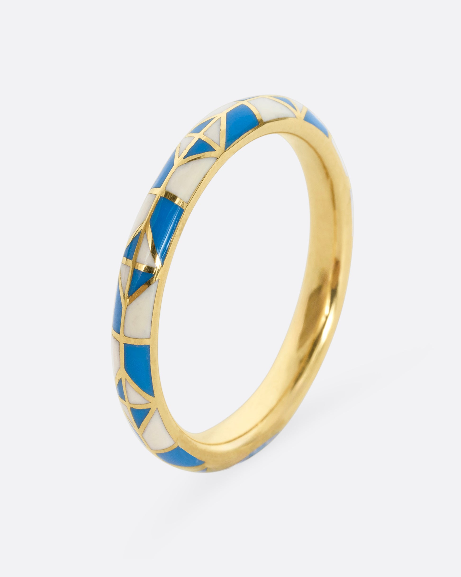 A yellow gold band ring with a turquoise and cream enamel patchwork pattern. Shown from the side.