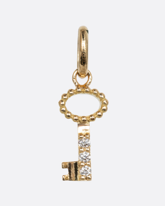 A yellow gold key charm with three white diamonds. Shown from the front.