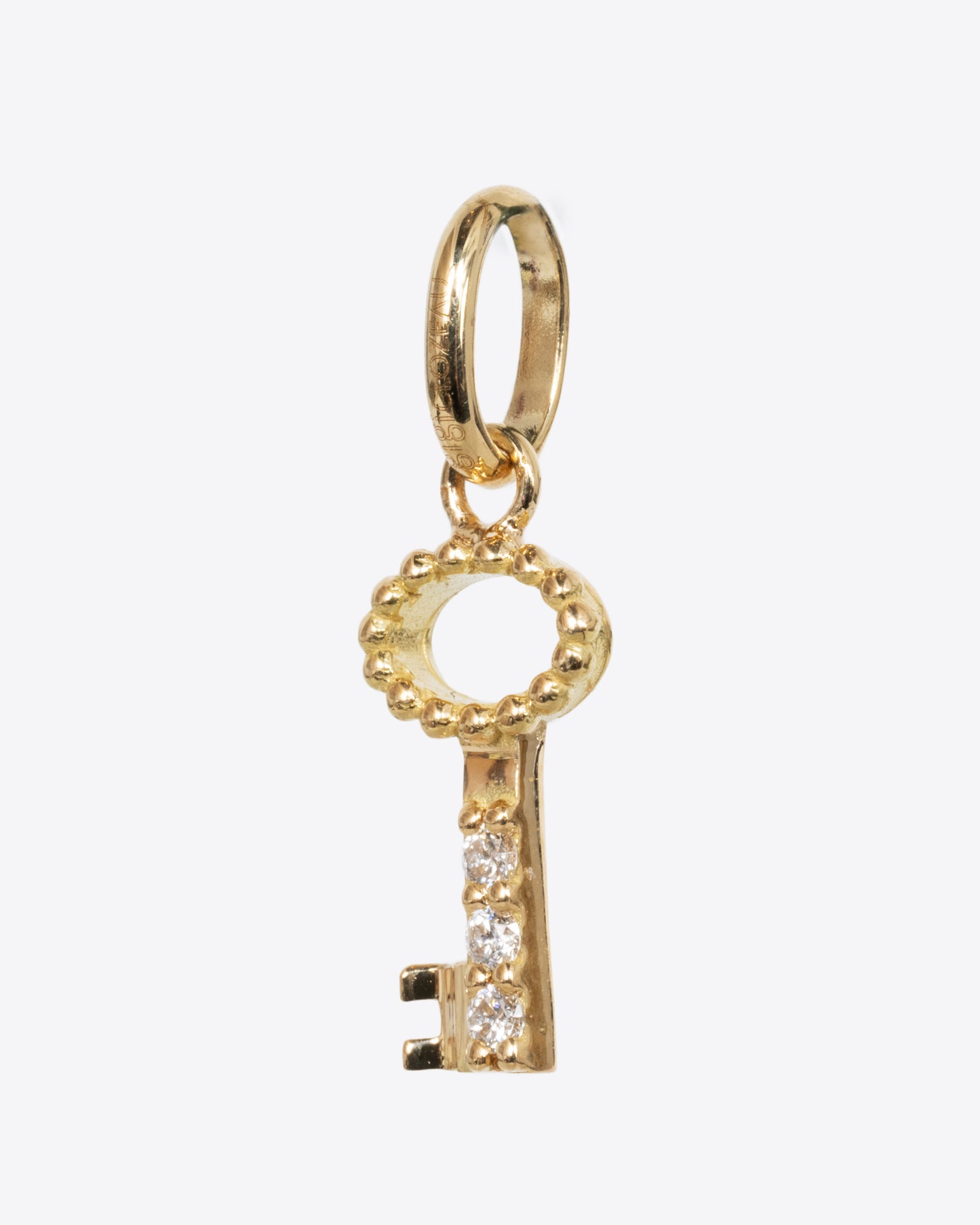 A yellow gold key charm with three white diamonds. Shown from the side.