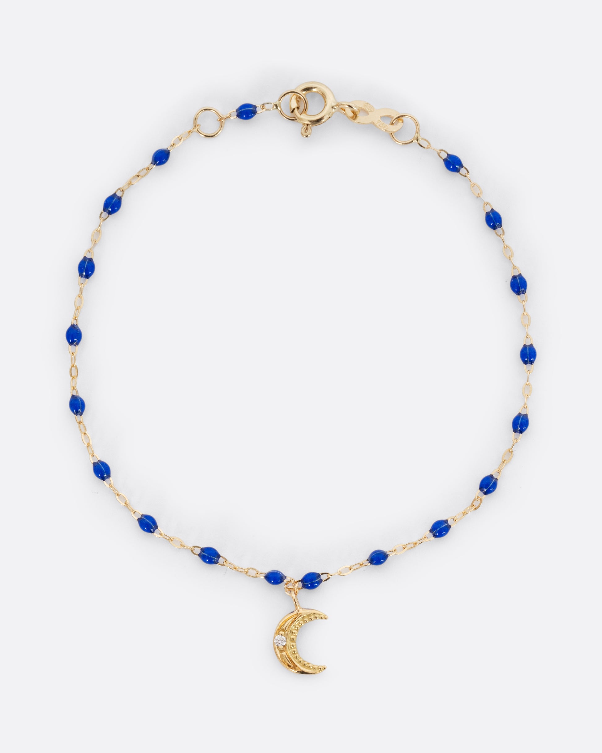 A yellow gold cable chain bracelet with blue resin droplets and a crescent moon charm. A single white diamond is set in the center of the crescent moon. Shown from the front.