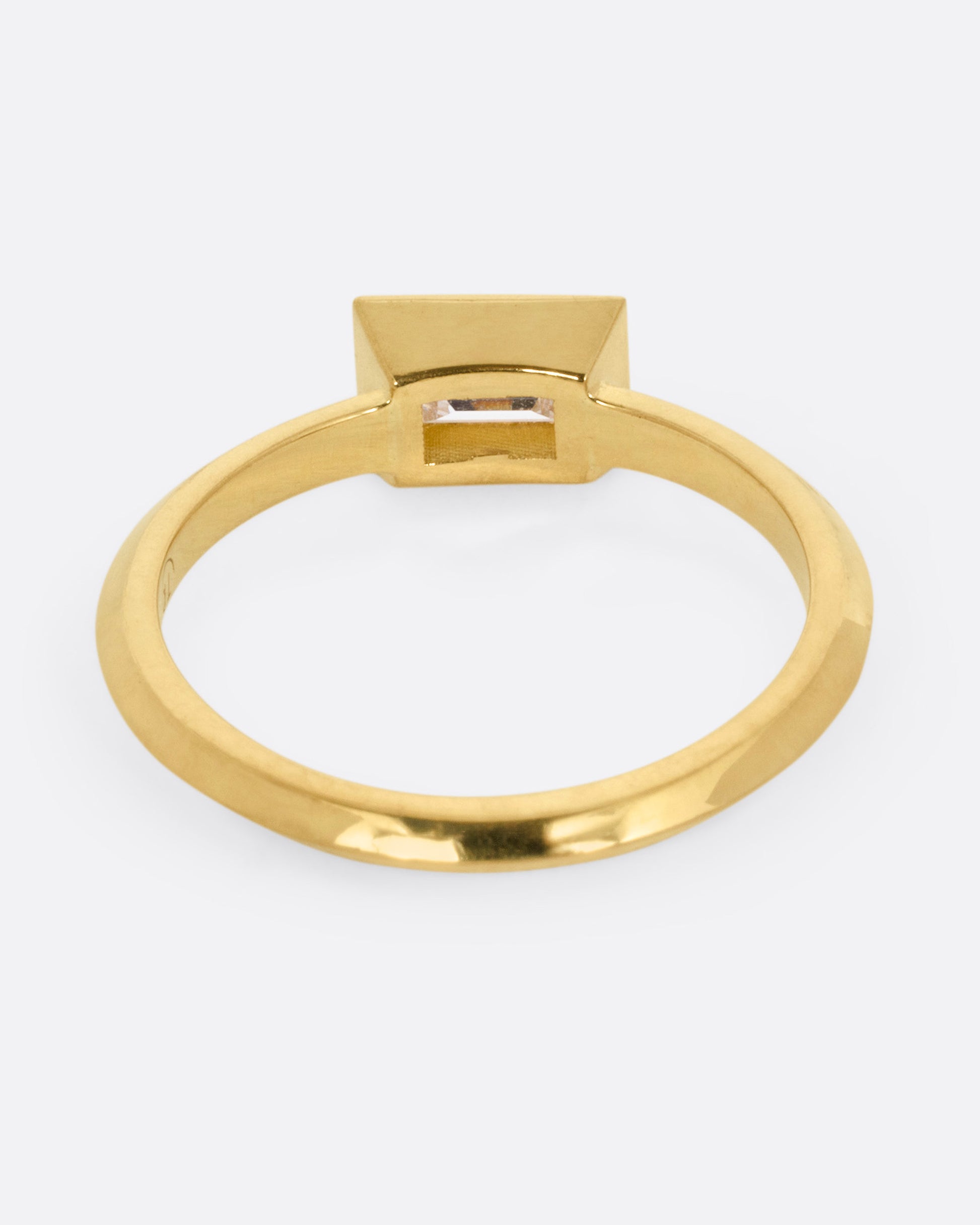 A yellow gold ring with a baguette diamond, shown from the back.