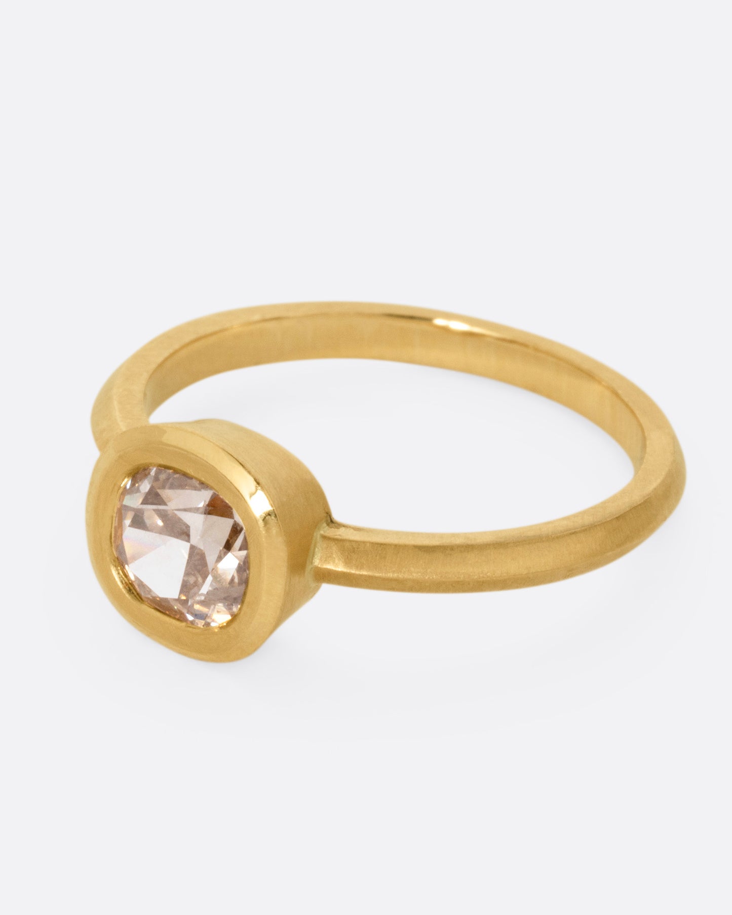A yellow gold ring with a cognac diamond, shown from the side.