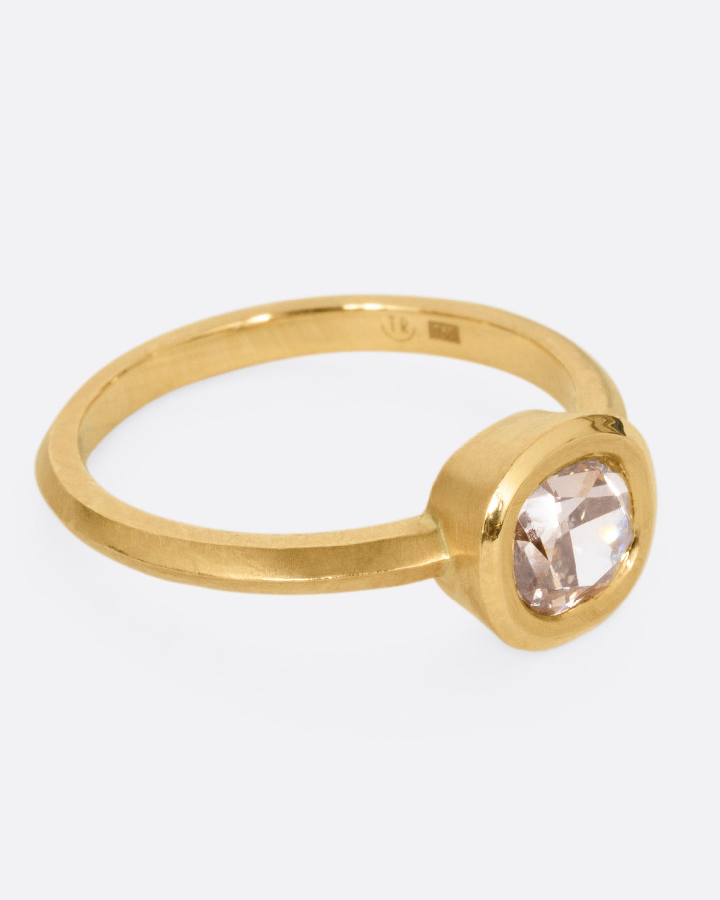 A yellow gold ring with a cognac diamond, shown from the side.