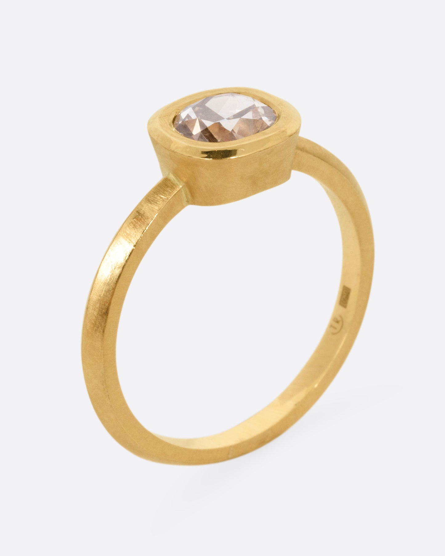 A yellow gold ring with a diamond, shown standing up from the side.