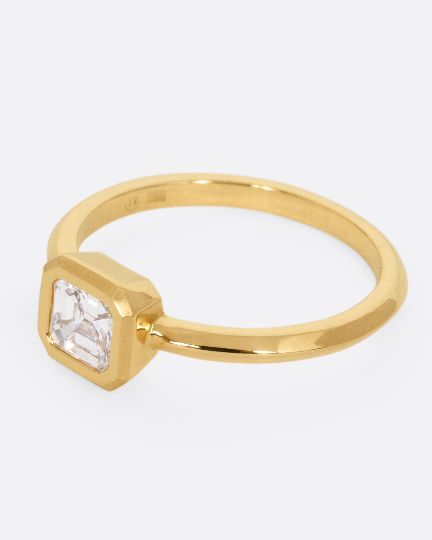 A yellow gold ring with a diamond, shown from the side.