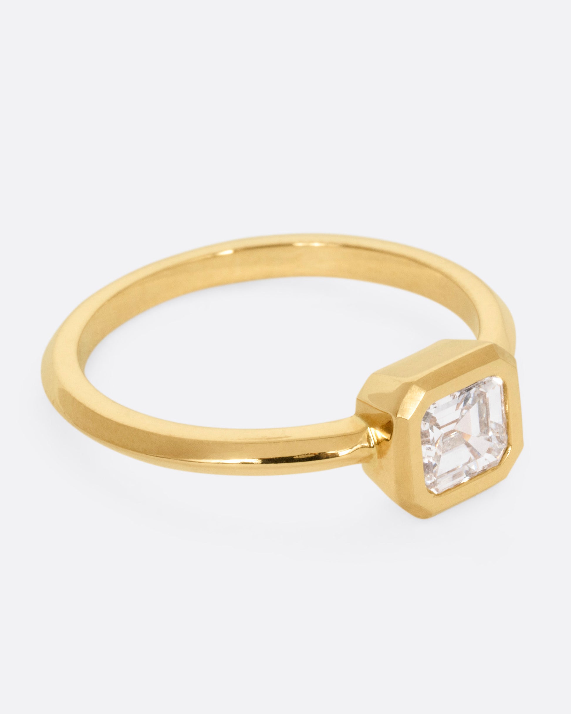 A yellow gold ring with a diamond, shown from the side.