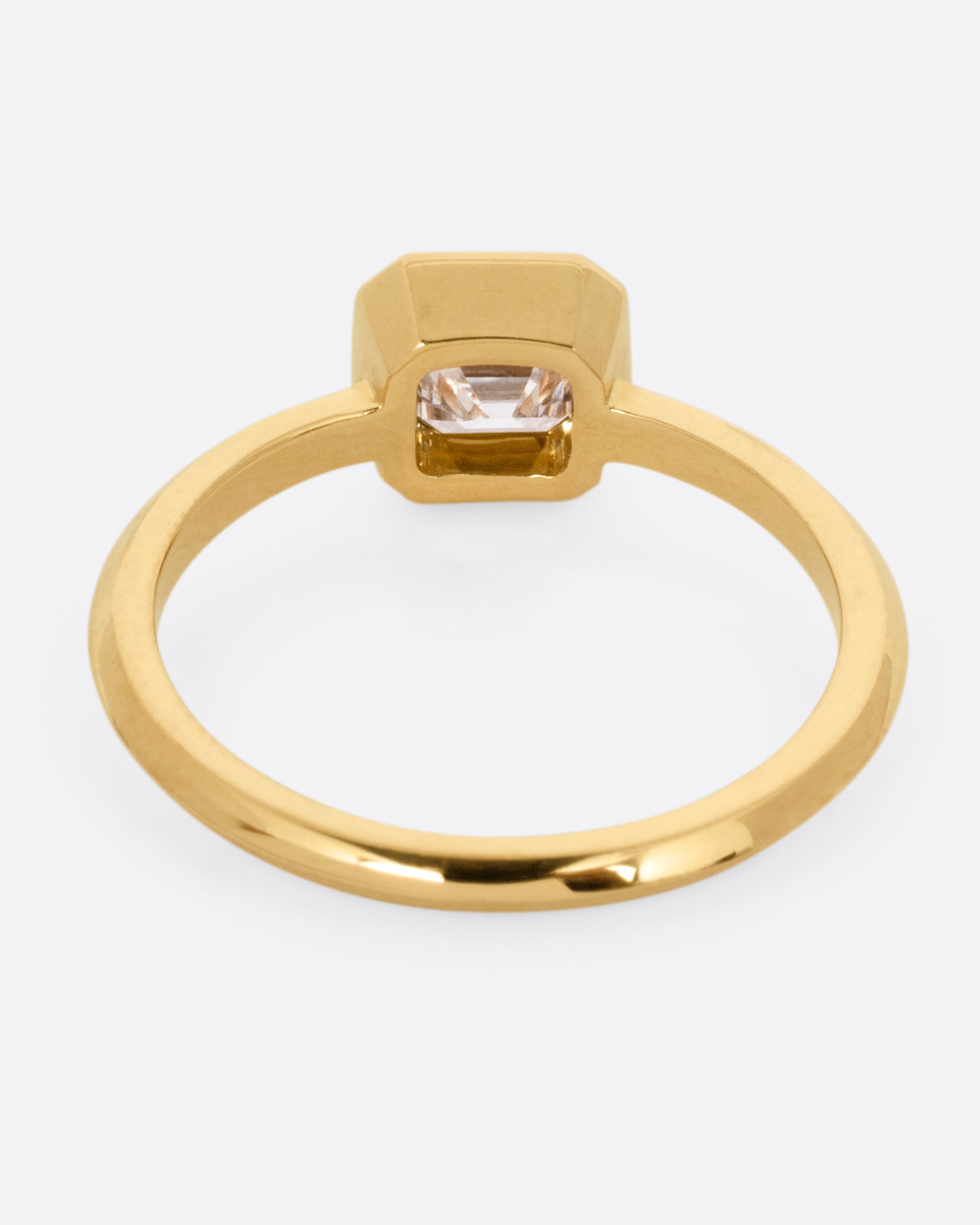 A yellow gold ring with a diamond, shown from the back.