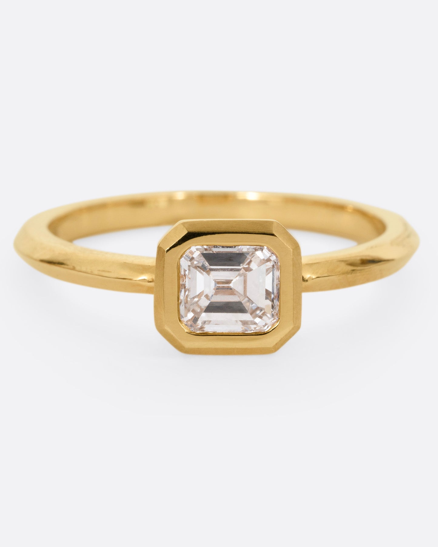 A yellow gold ring with a diamond, shown from the front.