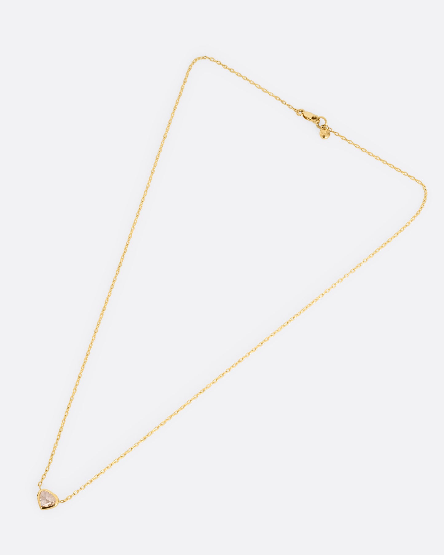 A yellow gold necklace with a natural organic heart shaped diamond, shown from the front.