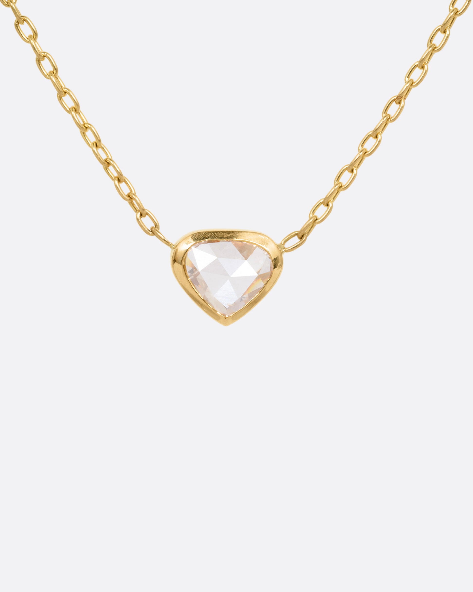A yellow gold necklace with a natural organic heart shaped diamond, shown from the front.