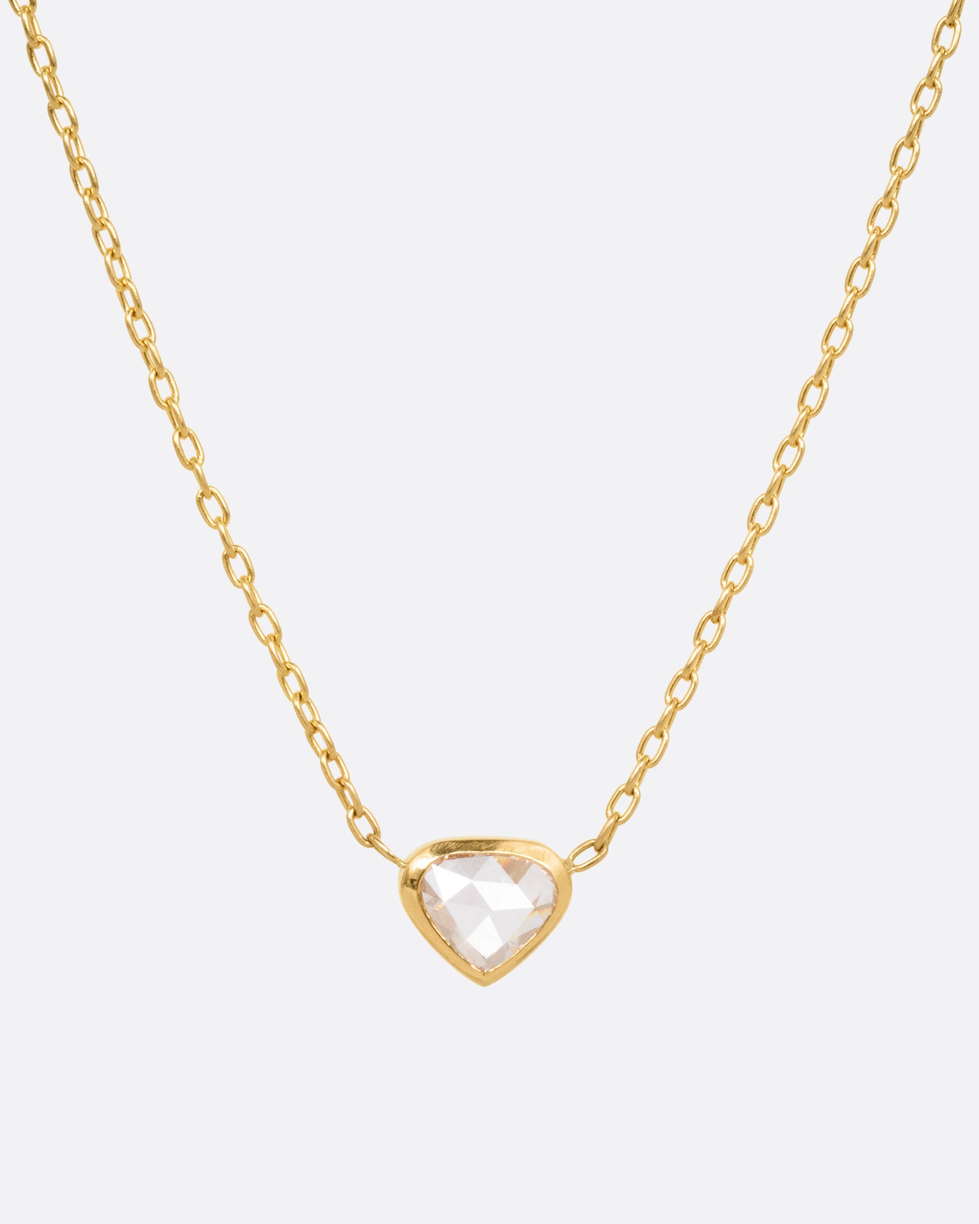 A yellow gold necklace with a natural organic heart shaped diamond, shown from the front.