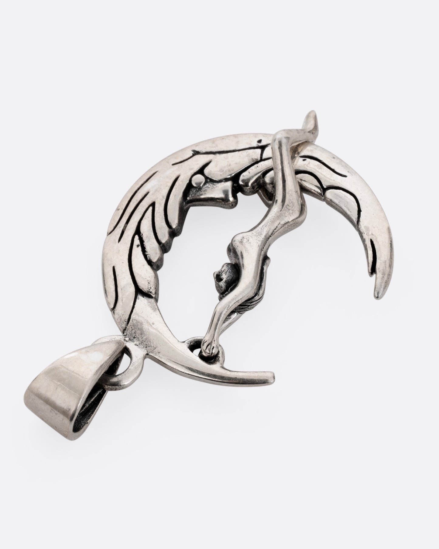 A silver pendant with a woman grasping a craggy crescent moon, shown from the back.