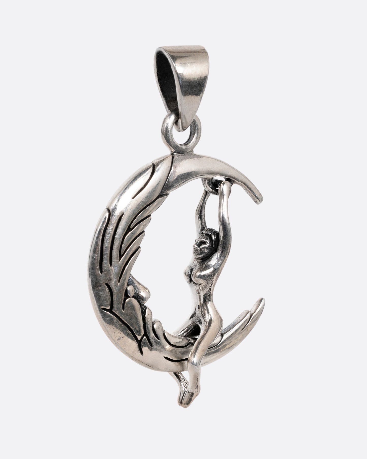 A silver pendant with a woman grasping a craggy crescent moon, shown from the side.