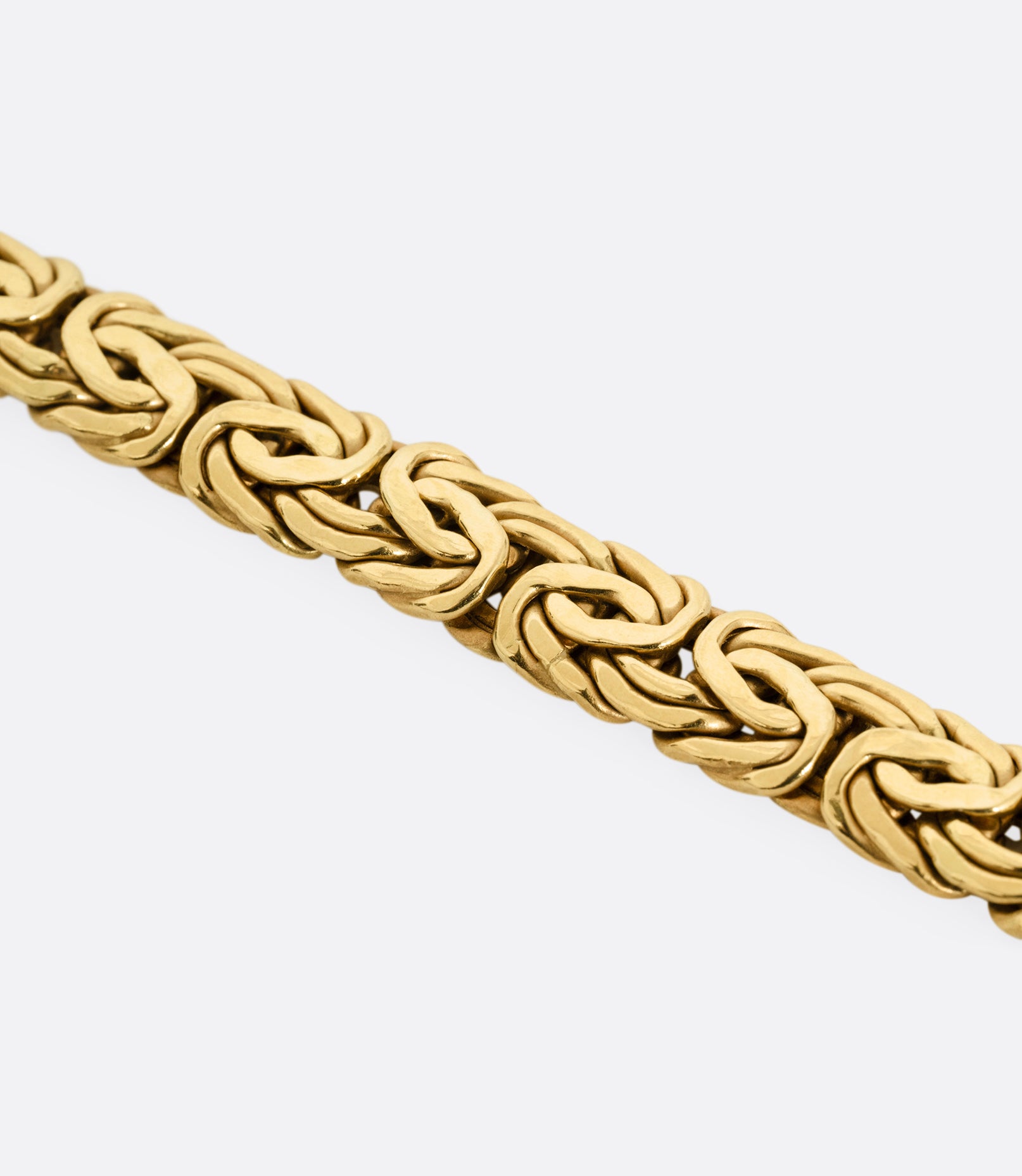 A close up of a yellow gold byzantine chain bracelet.