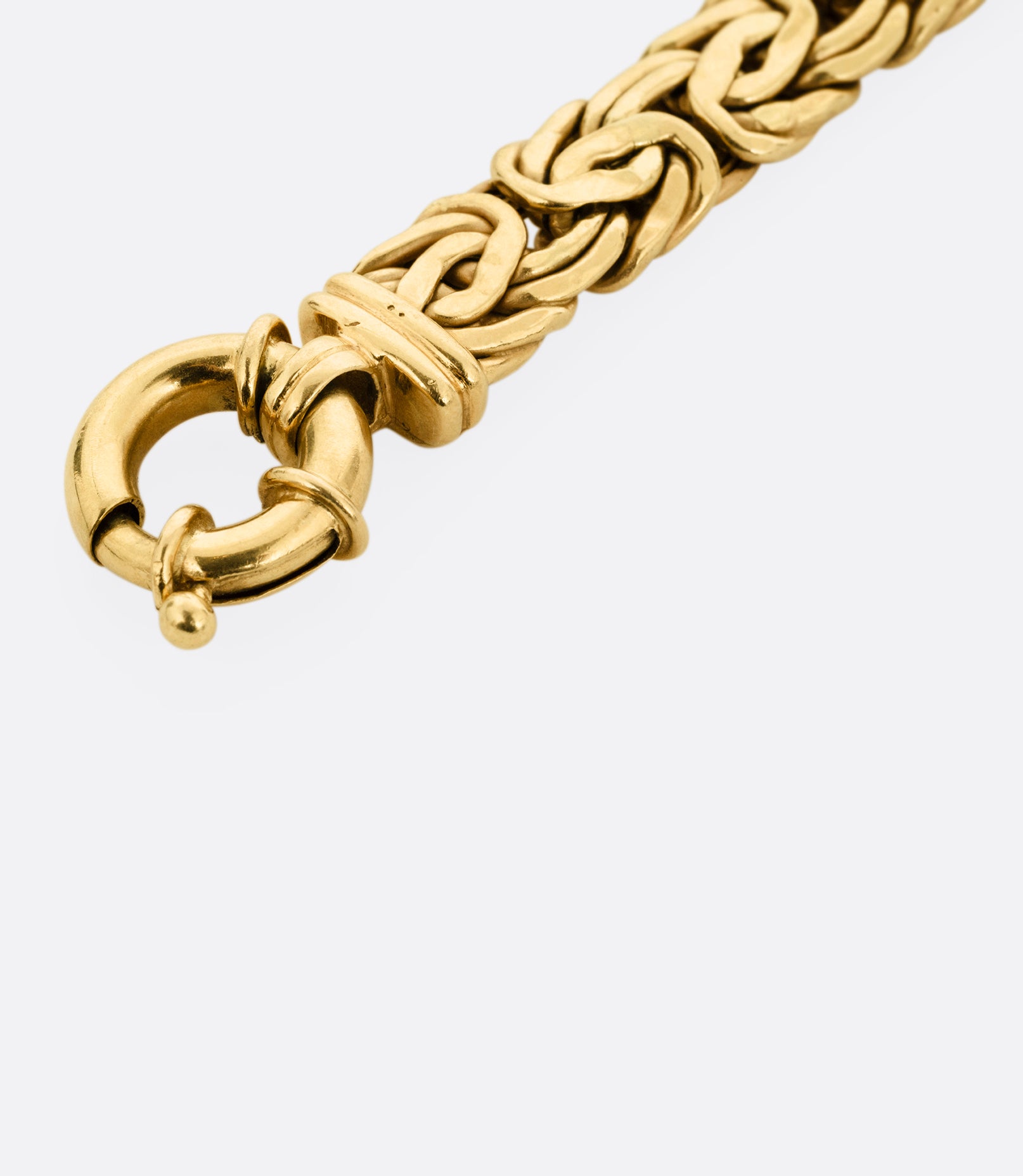 A close up of a yellow gold byzantine chain bracelet, shown from the front.
