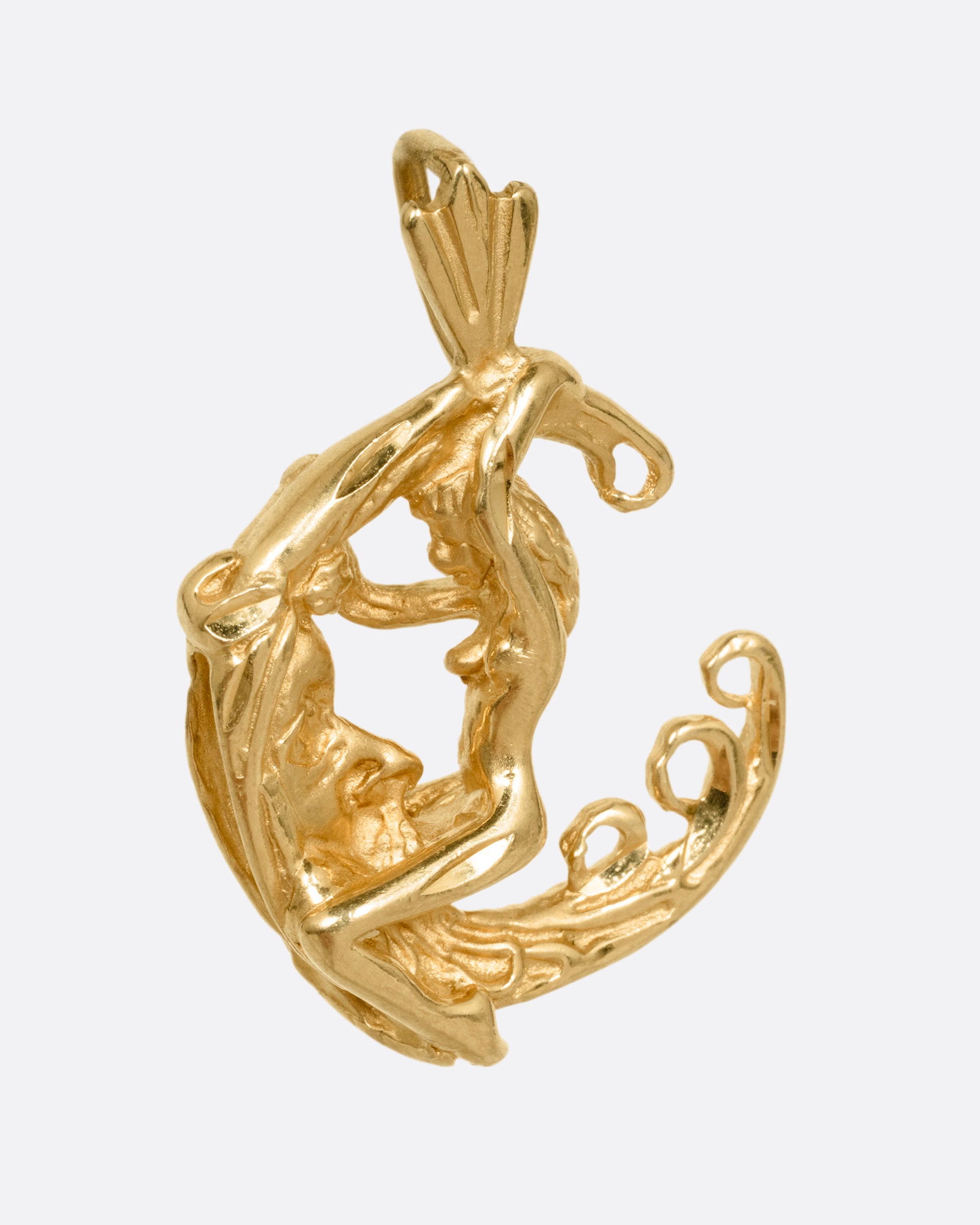 A yellow gold pendant with a woman astride a crescent moon. Shown from the side.
