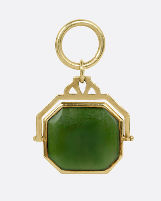 A yellow gold pendant with a spinning swath of jade, shown from the front.