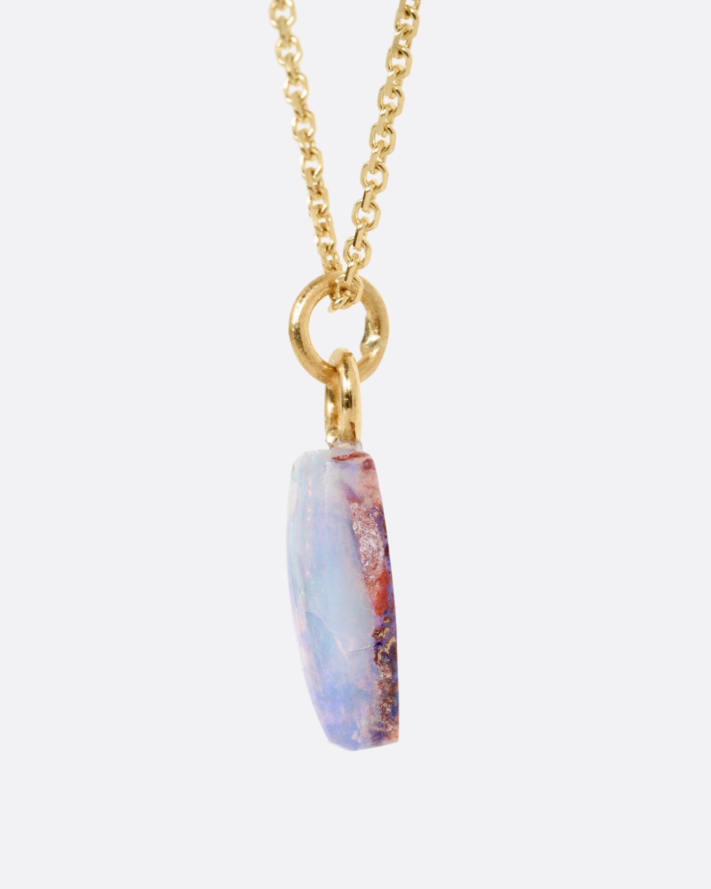 A yellow gold cable chain necklace with a fossilized Australian opal pendant. Shown from the side.