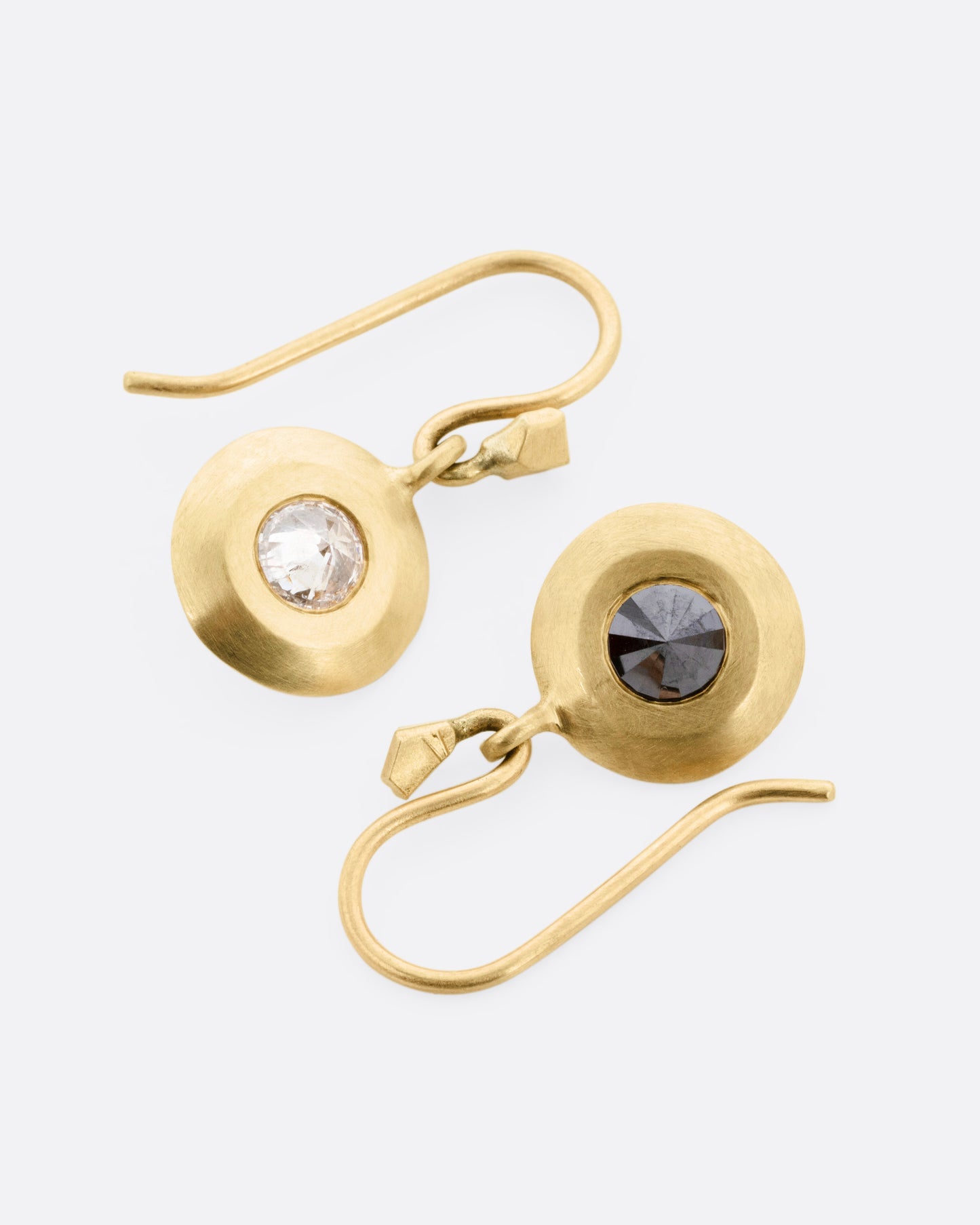 A pair of yellow gold drop earrings, each with reverse set black and gray diamonds. One earring is shown with the gray diamond exposed, the other with the black.