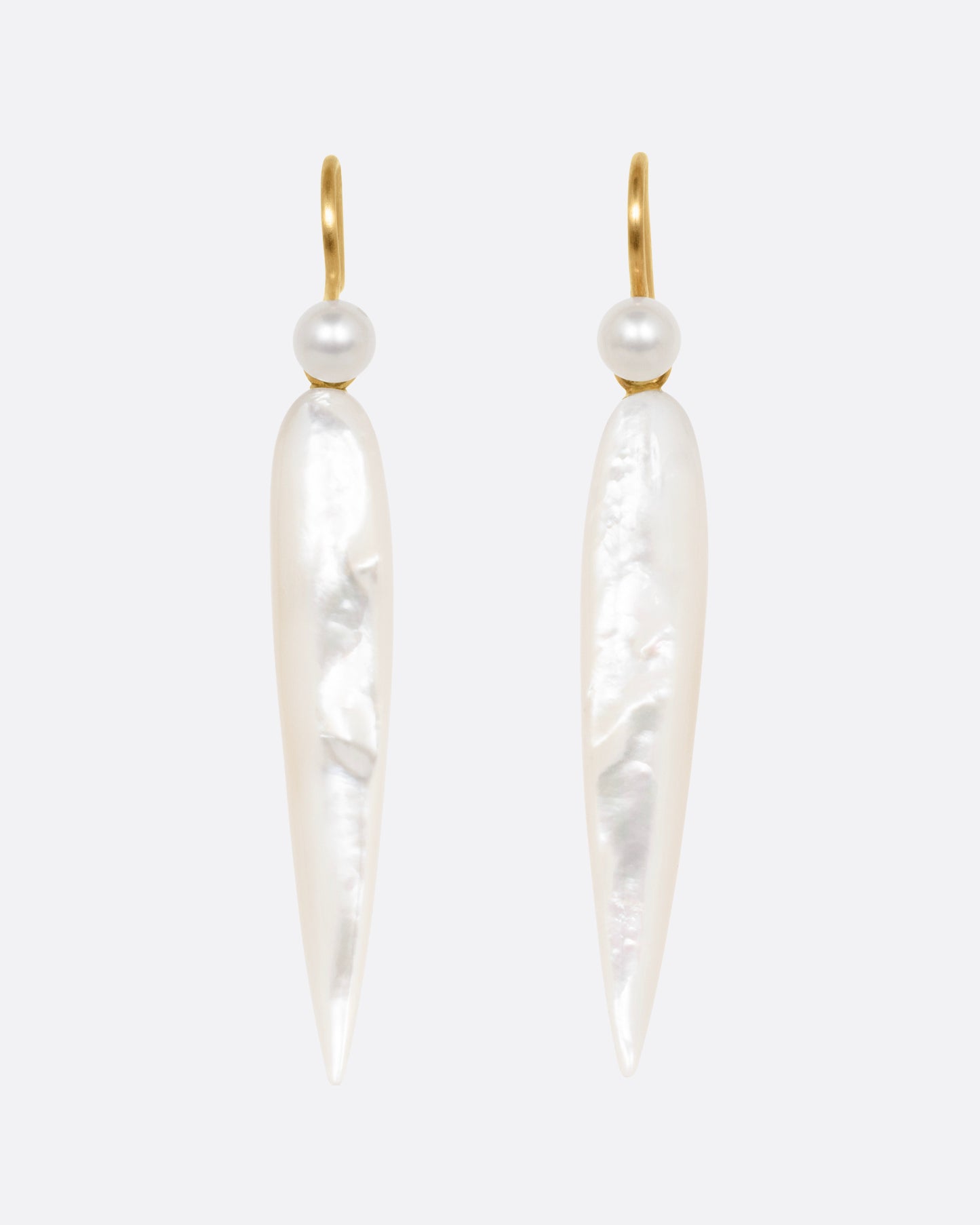 A pair of pointed mother of pearl drop earrings with yellow gold ear hooks, shown from the front.