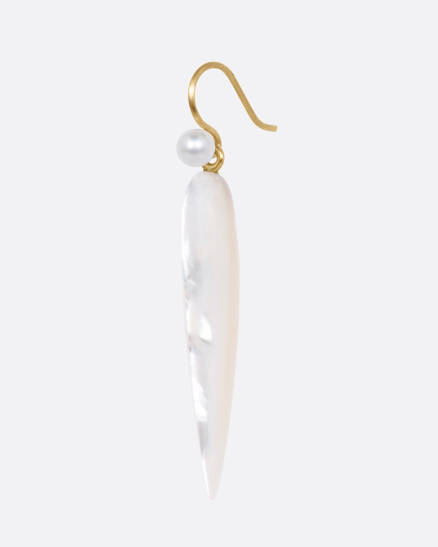 A pointed mother of pearl drop earring with yellow gold ear hooks, shown from the side.
