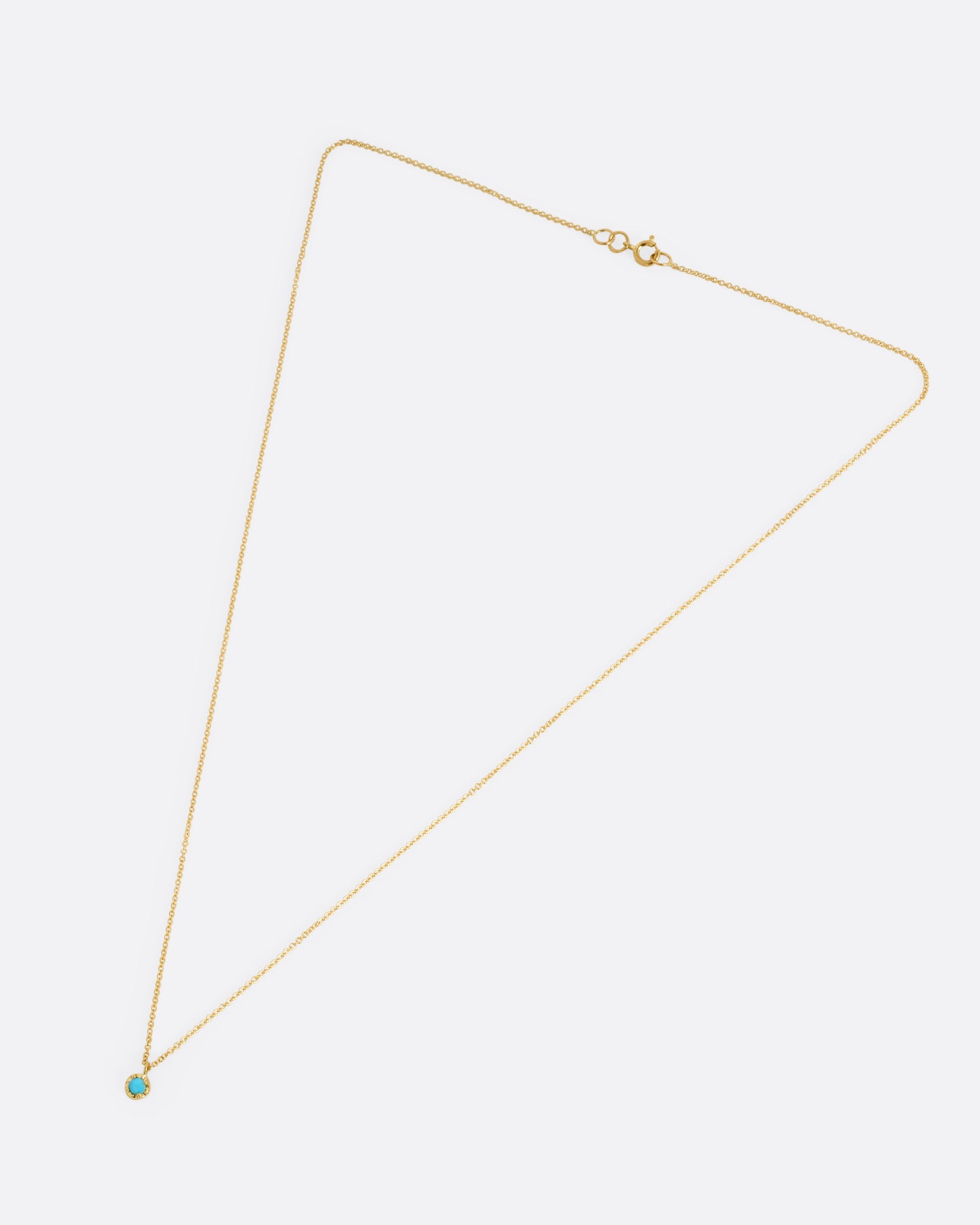 A yellow gold cable chain necklace with a  prong set turquoise, shown from the front.