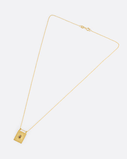 A yellow gold pendant necklace with a teardrop shaped salt and pepper diamond in a rectangular gold frame, with a double bail. Shown from the front.