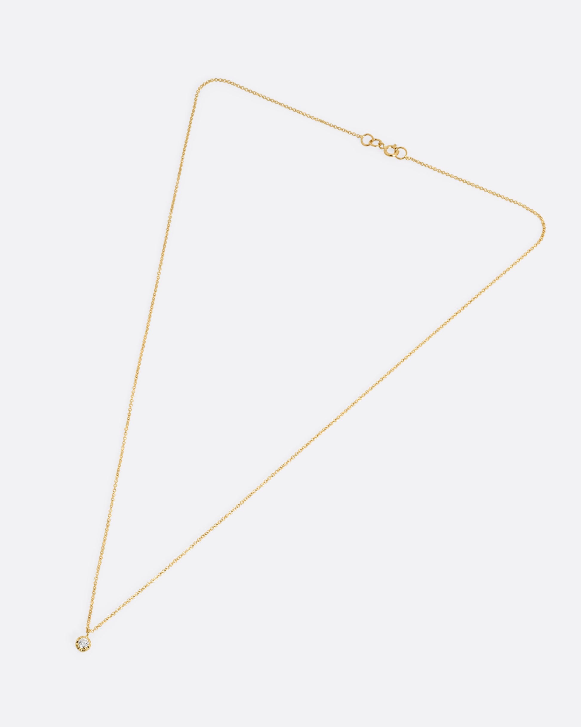 A yellow gold cable chain necklace with a  prong set white diamond, shown from the front.