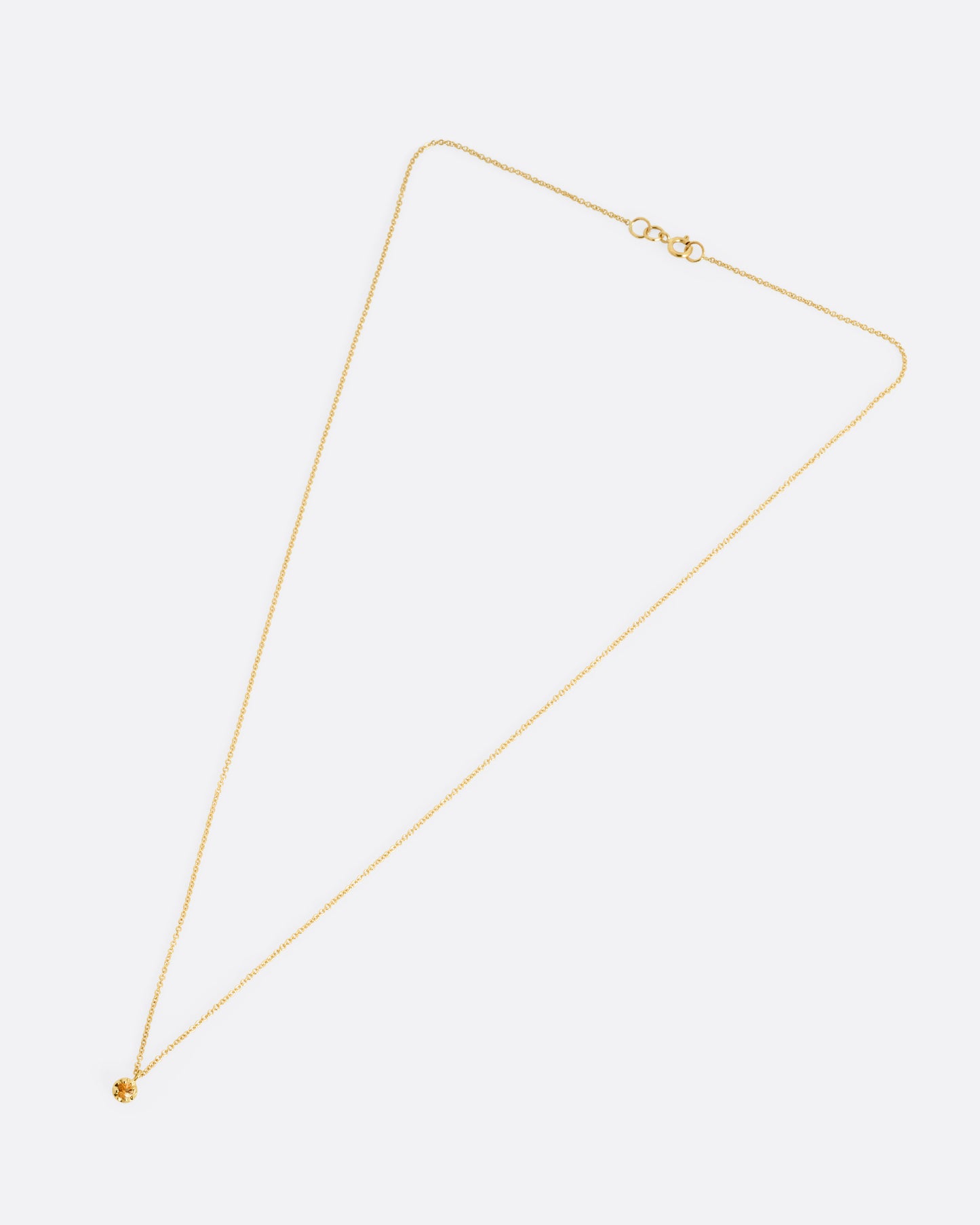 A yellow gold cable chain necklace with a  prong set citrine, shown from the front.