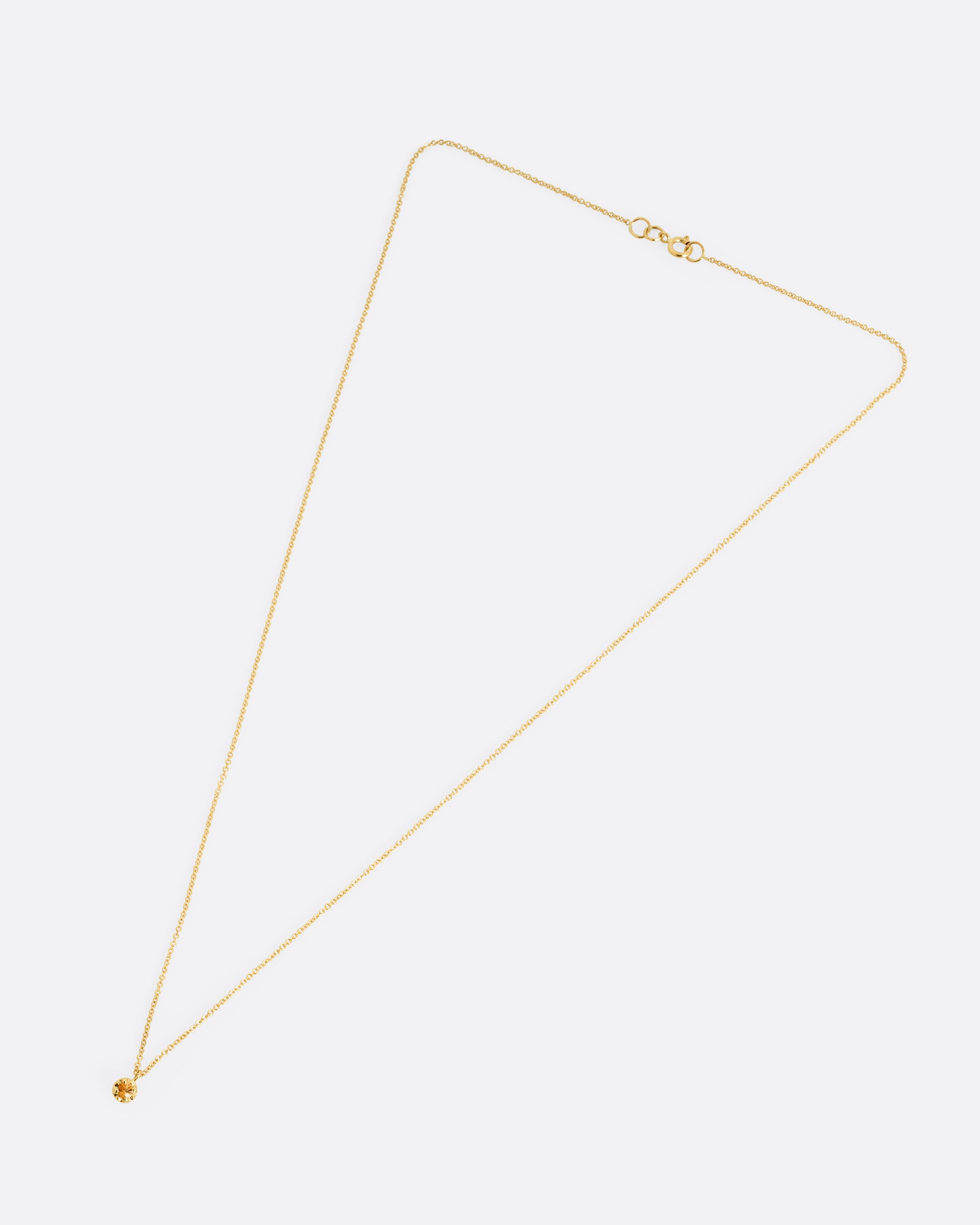 A yellow gold cable chain necklace with a  prong set citrine, shown from the front.