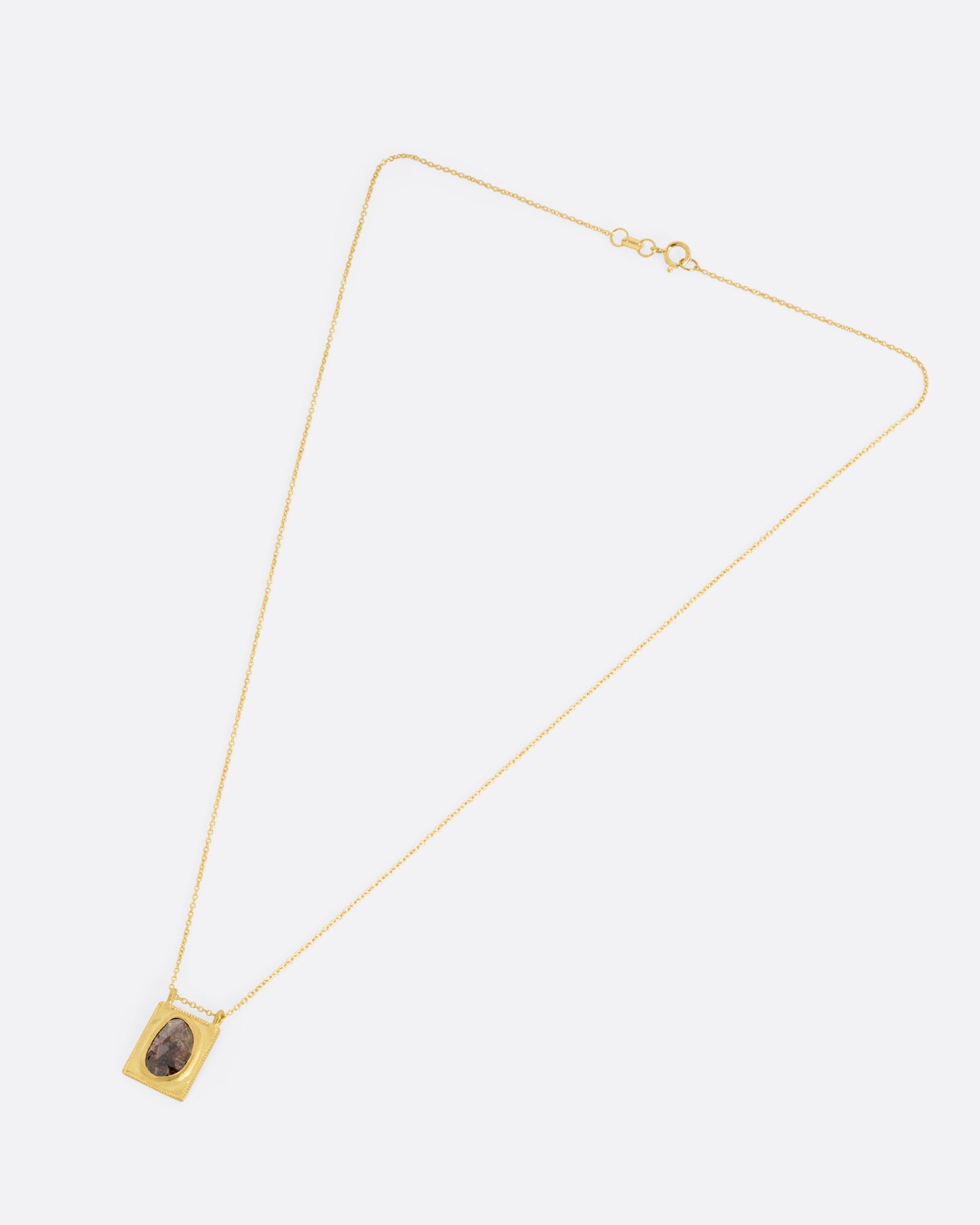 A yellow gold pendant necklace with a rose cut salt and pepper diamond in a rectangular gold frame, with a double bail. Shown from the front.