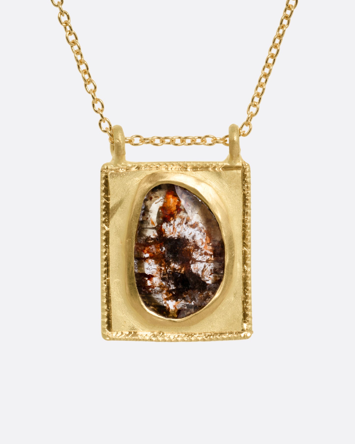 A yellow gold pendant necklace with a rose cut salt and pepper diamond in a rectangular gold frame, with a double bail. Shown from the front.