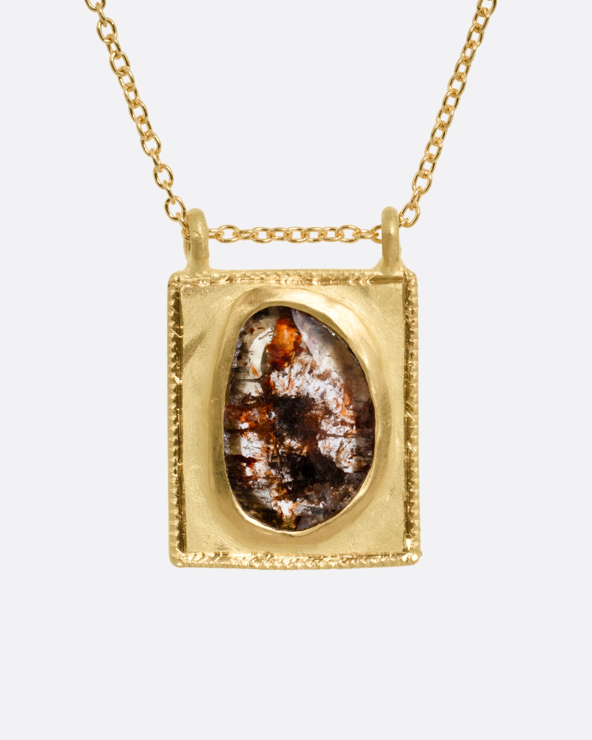 A yellow gold pendant necklace with a rose cut salt and pepper diamond in a rectangular gold frame, with a double bail. Shown from the front.