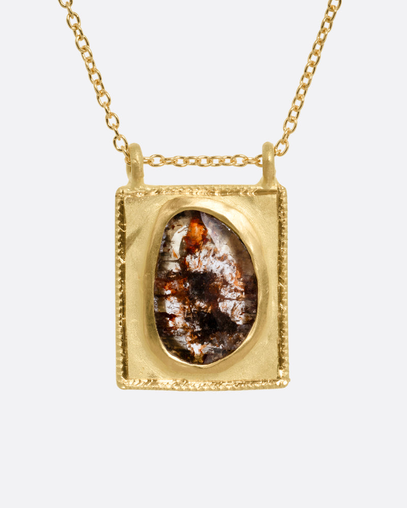 A yellow gold pendant necklace with a rose cut salt and pepper diamond in a rectangular gold frame, with a double bail. Shown from the front.
