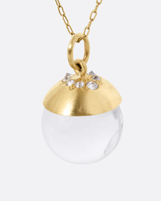 A yellow gold cable chain necklace with a quartz sphere pendant topped with gold and reverse set diamonds. Shown from the front.