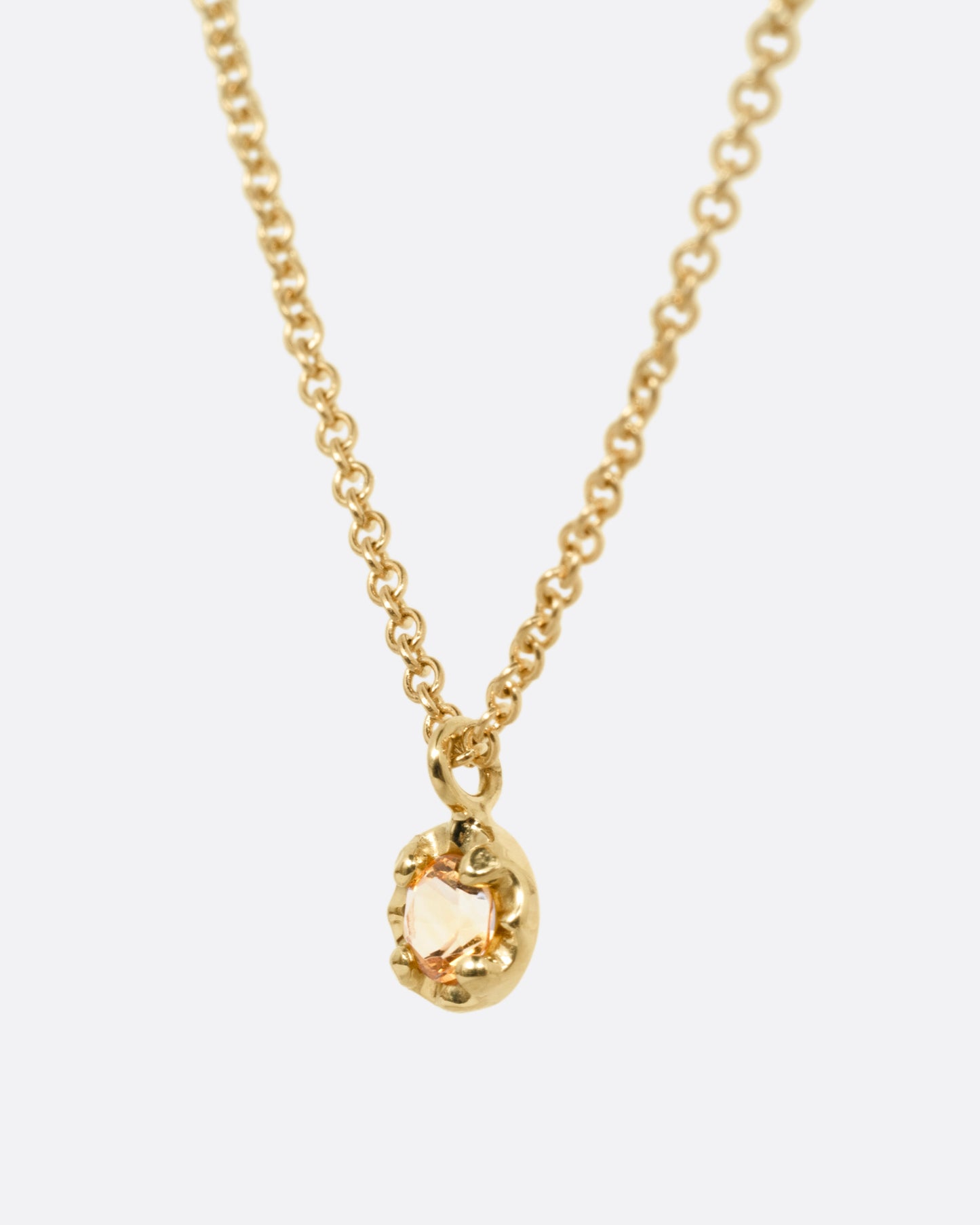 A yellow gold cable chain necklace with a  prong set citrine, shown from the side.