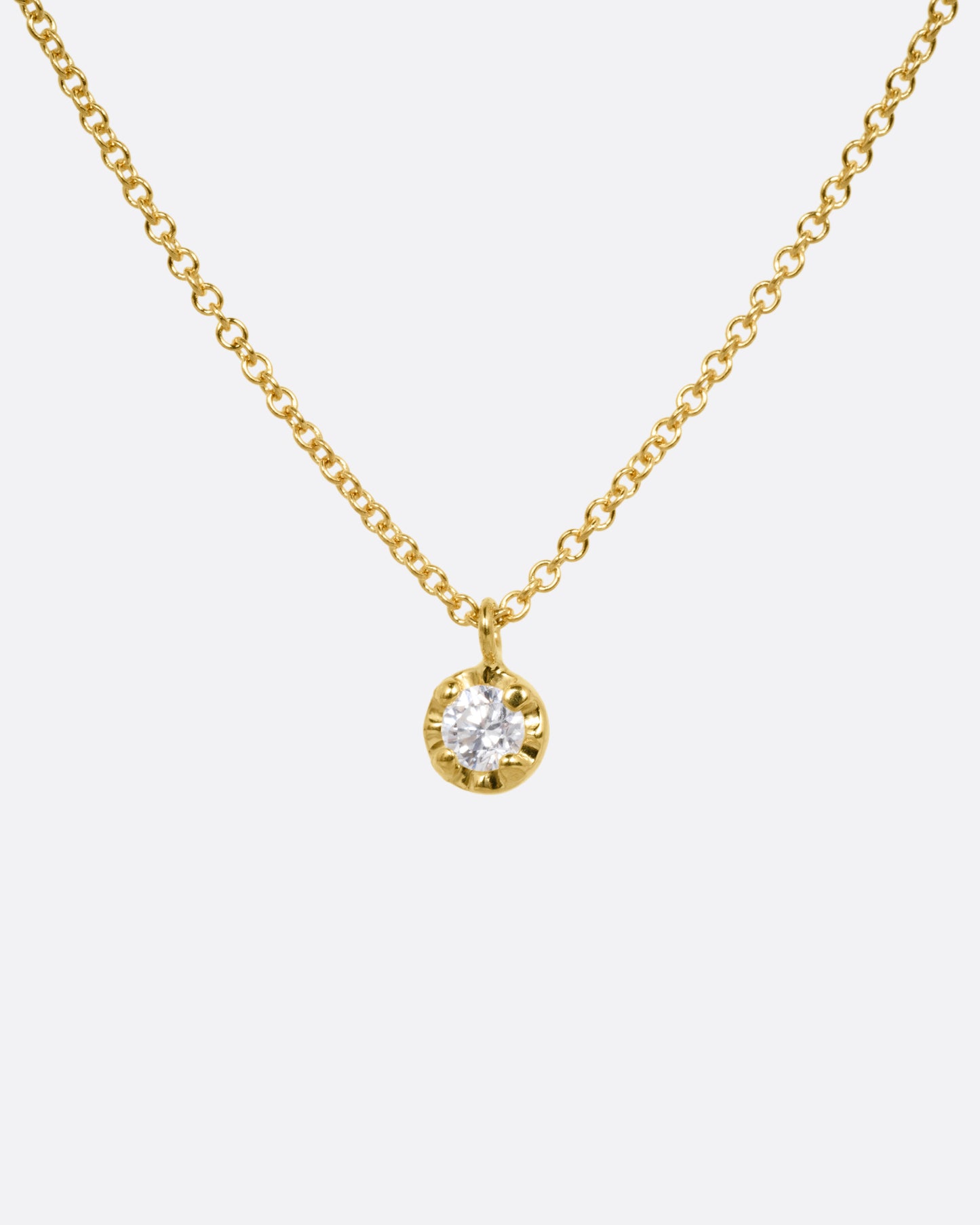 A yellow gold cable chain necklace with a  prong set white diamond, shown from the front.