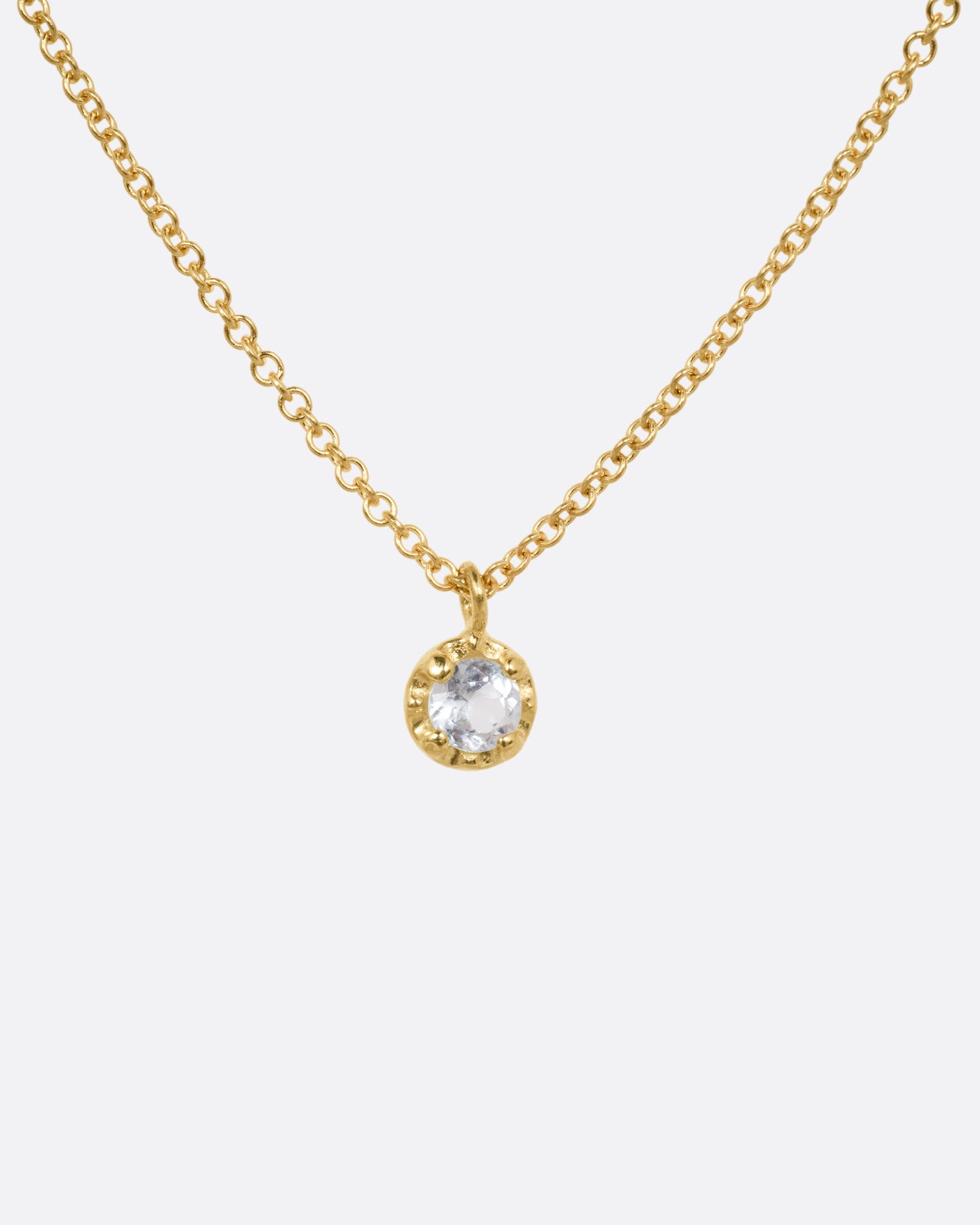 A yellow gold cable chain necklace with a  prong set aquamarine, shown from the front.